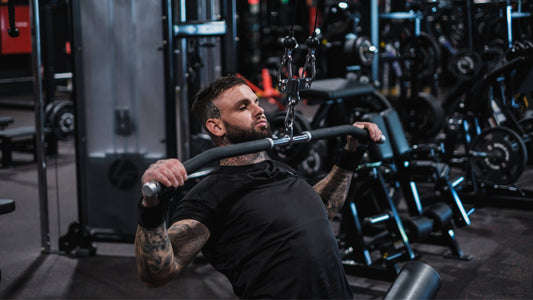 Man performing a lat pulldown exercise in a modern gym, focusing on back strength and fitness goals