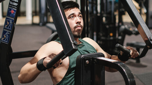 Man using a seated chest press machine in the gym, wearing lifting straps for added grip support